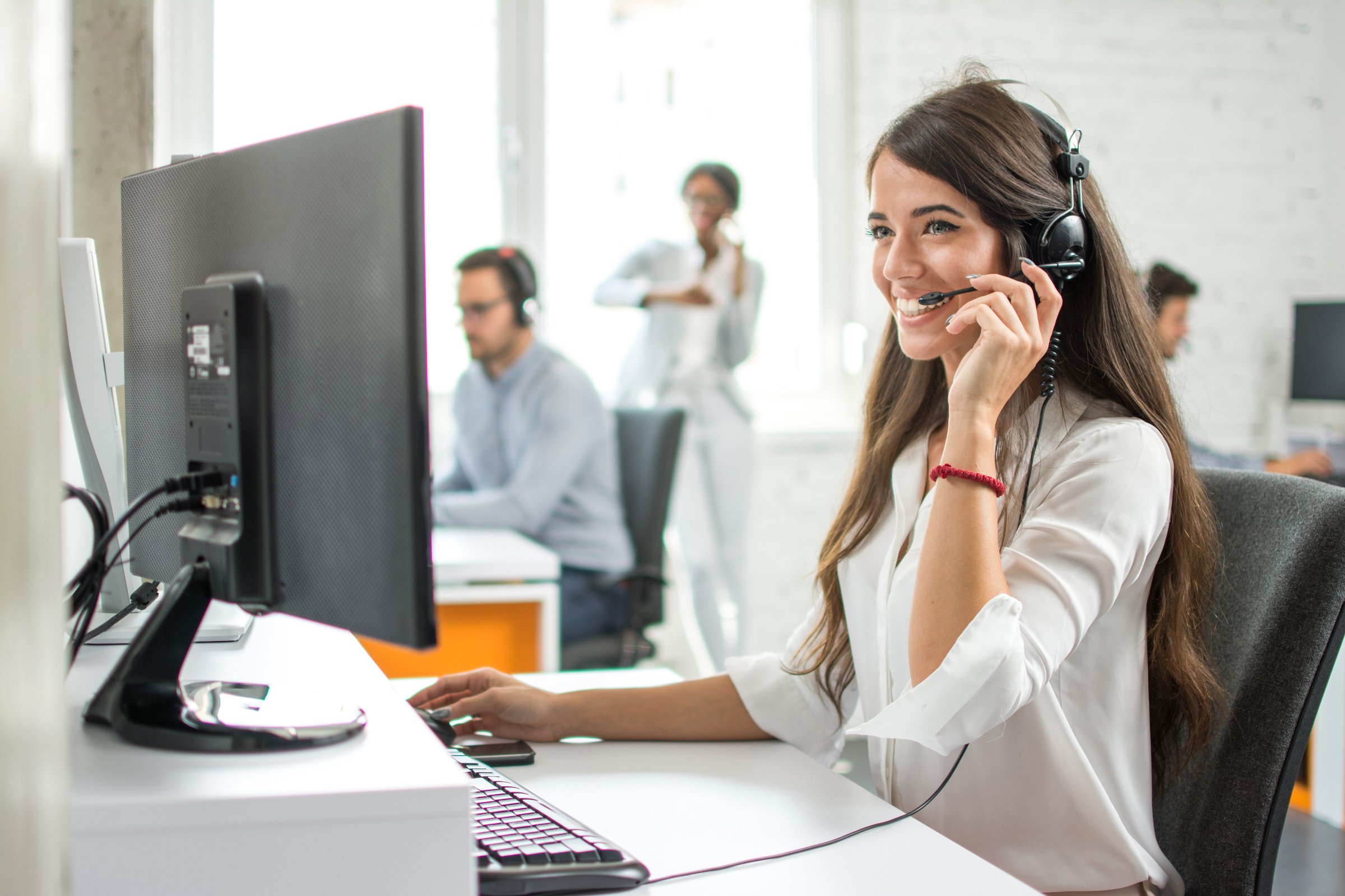 Happy smiling female customer service operator working on computer in office